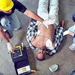 EMT using a defibrillator on man lying down 